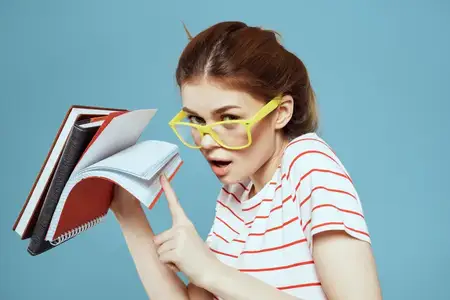 Красивая студентка с блокнотами и в жёлтых очках на синем фоне