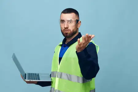 Красивый молодой строитель в каске и рабочей одежде на белом фоне
