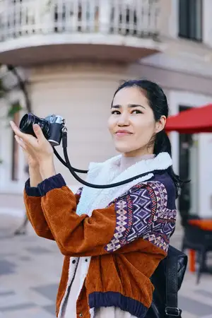 Сцена уличной фотографии, показывающая улыбающегося фотографа с камерой на улице, яркую моду, откровенный творческий процесс, городское исследование и повествование