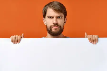 Эмоциональный мужчина держит белый баннер на оранжевом фоне