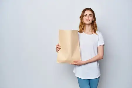 Женщина в белой футболке держит пакет с продуктами, совершая покупки