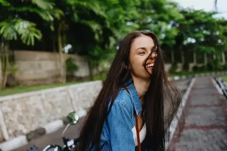 Портрет улыбающейся брюнетки, идущей на улице на фоне пальм в тропиках