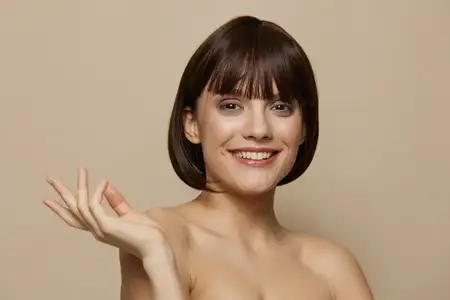 Красивая женщина с косметикой, привлекательный взгляд, позирует на бежевом фоне, демонстрируя чистую кожу