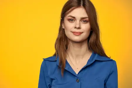 Женщина в голубой рубашке на желтом фоне, портрет крупным планом, рыжие волосы, модель