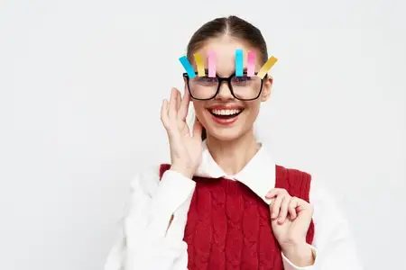 Игривый портрет молодой женщины с разноцветными скрепками, прикрепленными к ее oversized-очкам