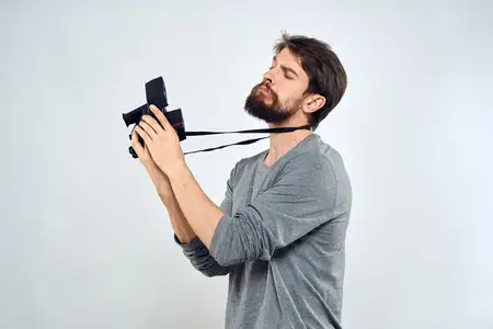Фотограф-мужчина, профессиональная камера, работа в студии, технологии, современное искусство, светлый фон