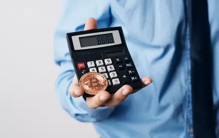 Мужчина держит в руках криптовалюту Bitcoin, калькулятор роста цены, финансовые технологии