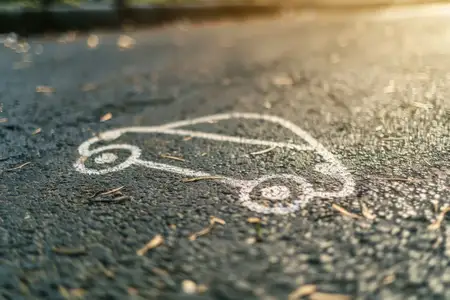 Простой контур автомобиля, нарисованный мелом на текстурированной асфальтовой поверхности, освещенный мягким светом заката