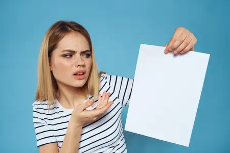 Эмоциональная женщина держит в руках лист бумаги