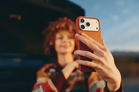 Активный образ жизни на улице: женщина делает селфи на смартфон, рука близко к экрану, на заднем плане автомобиль