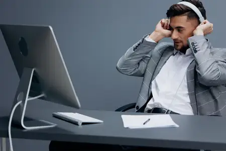 Красивый мужчина работает за компьютером в наушниках на изолированном фоне