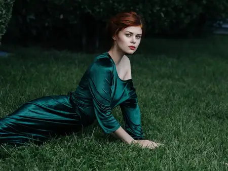 Женщина в зеленом платье лежит в саду среди декоративных элементов на фоне природы