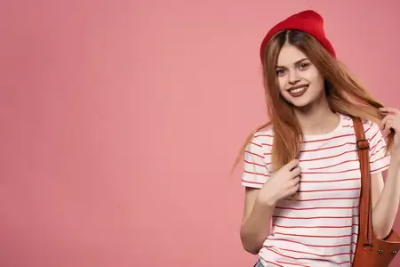 Симпатичная молодая женщина в модной одежде и красной шляпе, воплощающая современный стиль