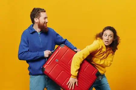 Женщина и мужчина улыбаются, в руках чемоданы — желтый и красный, улыбаются весело и криво, на желтом фоне, собираются в путешествие, семейный отпуск, молодожены
