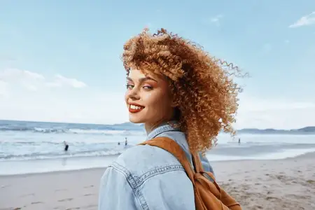 Улыбающаяся женщина на пляже, обретающая свободу и счастье, запечатленная в широкоугольном портрете