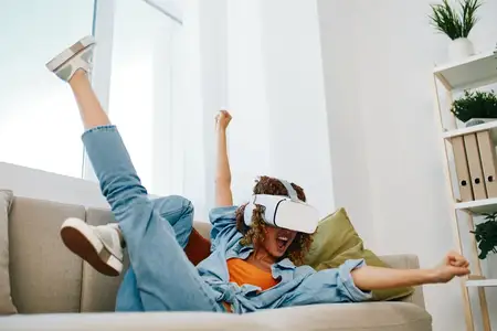 Блаженство виртуальной реальности: радостная женщина в футуристических VR-очках наслаждается кибер-игрой дома