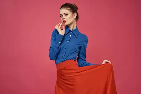 Женщина в синей рубашке с красными кубиками на розовом фоне, веселые эмоции, модель, обрезанный вид