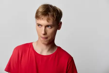 Непринужденная студийная съемка: мужчина в красной рубашке с озадаченным выражением лица, акцент на мимике, передающей любопытство, сомнение и спонтанную мысль