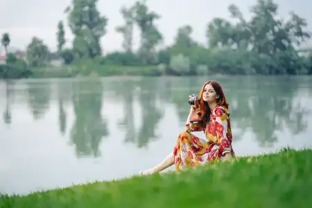 Женщина в платье с фотоаппаратом на природе, занимается фотографией как хобби