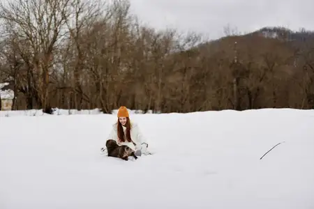 Женщина играет в снегу с собакой
