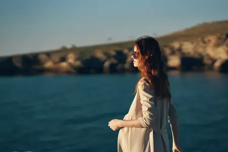 Модель в очках, женщина идет по пляжу у моря, вид сбоку