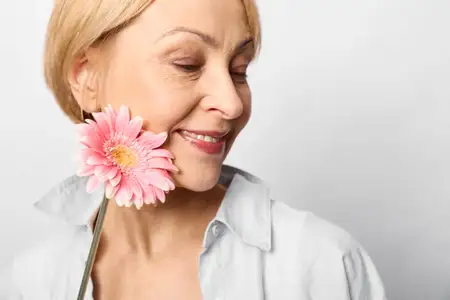 Женщина, цветок, розовый, портрет, зрелая, улыбающаяся, вдыхающая аромат, спокойная, студия, крупный план, бьюти-снимок по уходу за кожей, мягкий свет, безмятежная эмоция, аромат, весеннее цветение