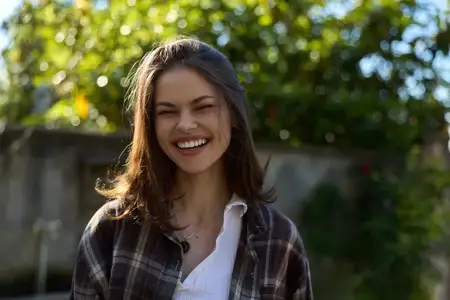 Лайфстайл-портрет улыбающейся женщины на улице в повседневной клетчатой рубашке