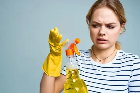Женщина в полосатой футболке занимается уборкой с использованием моющего средства