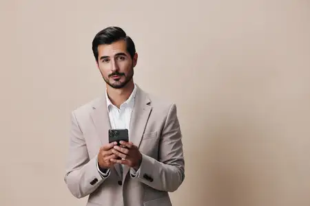Улыбающийся мужчина в деловом костюме держит смартфон в студии