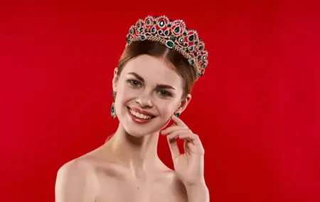 Портрет уверенной женщины на красном фоне с короной на голове