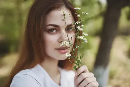 Весёлая женщина держит цветы, символизируя солнце, свободу и путешествие