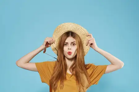Улыбающаяся женщина в шляпе, модной одежде, с косметикой, кадрированный вид