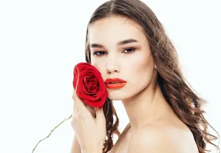 Женщина с красным цветком возле лица, чистая кожа, косметология, модель