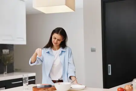 Женщина стоит на кухне с миской хлопьев и миской молока, готовя завтрак утром