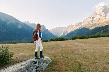Женщина-турист в горах с рюкзаком на лугу, пейзаж, поход, природа