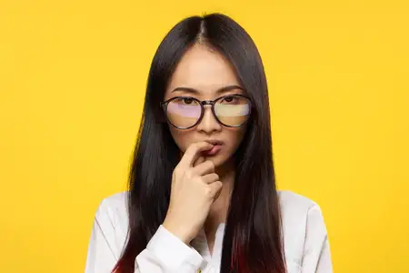 Привлекательная женщина в очках, элегантный стиль, привлекательный взгляд, палец возле губ, жёлтый фон