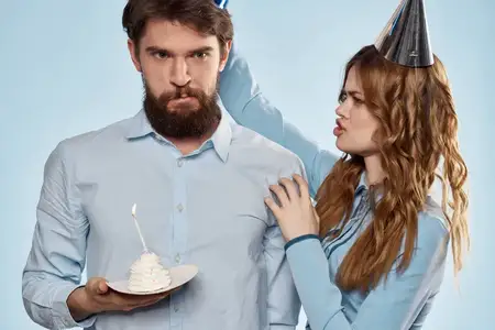 Весёлые мужчина и женщина с тортом на тарелке на корпоративной вечеринке