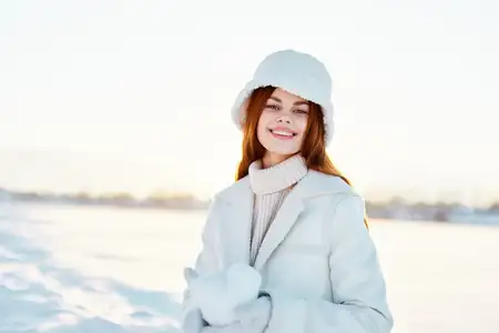 Красивая женщина улыбается, прогуливаясь в зимнем настроении