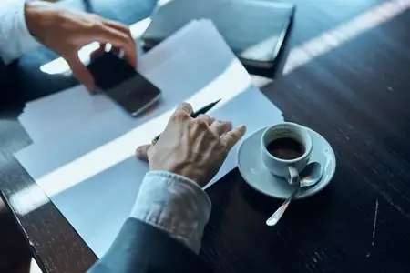 Бизнесмен в кафе с документами и чашкой кофе на столе, официальная работа