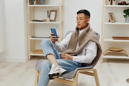 Красивый мужчина дома со смартфоном в руке сидит в кресле, интернет