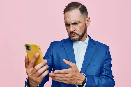 Фигура руководителя демонстрирует задумчивое настроение и решительную позу во время взаимодействия со смартфоном, намекая на стратегию, общение и уверенное лидерство на цветном студийном фоне