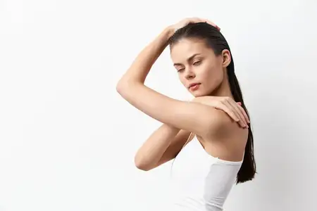Элегантный портрет женщины с длинными мокрыми волосами, которая нежно касается своего плеча