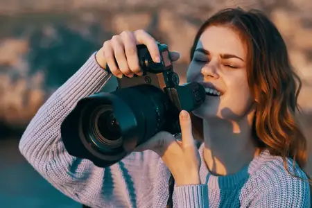 Счастливая женщина-фотограф с камерой в горах на природе, на заднем плане река