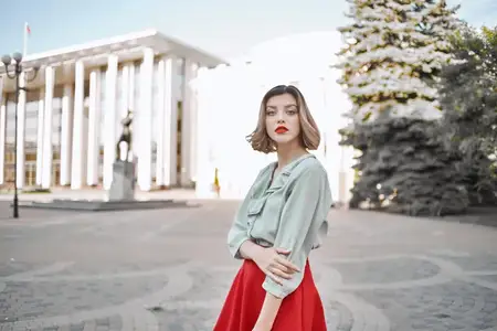 Симпатичная женщина в красной юбке прогуливается по городу на свежем воздухе