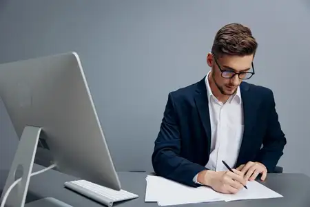 Красивый бизнесмен в очках работает за компьютером в офисе