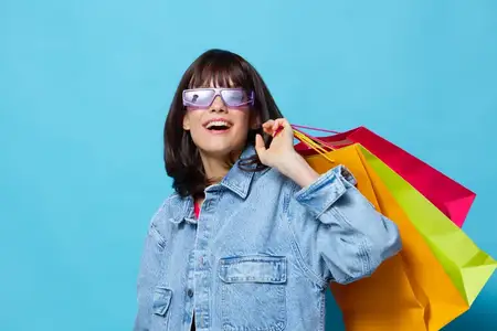 Красивая женщина в джинсовых куртках с разноцветными пакетами для покупок, обрезанный вид