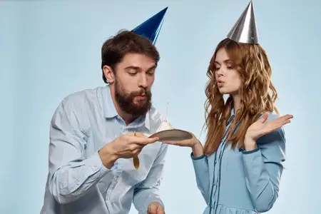 Корпоративный день рождения: молодые мужчина и женщина с тортом на изолированном фоне, диско-вечеринка