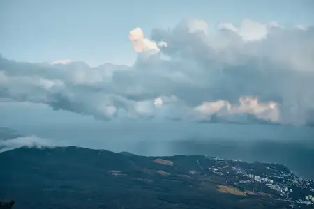 Живописный вид на океан с вершины горы, в небе пролетает самолёт