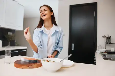 Женщина стоит перед кухонным столом, на котором стоит миска с едой, в уютной домашней обстановке