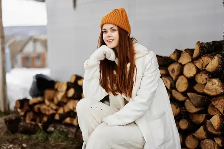 Женщина держит дрова для печи, размышляя о цене, природе и отдыхе во время зимних праздников